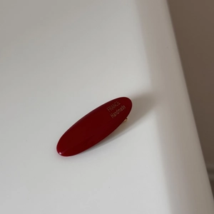 Detail of burgundy oval acetate hair clip with golden France Handmade lettering