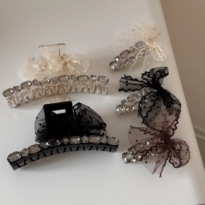 Detail of polka dot tulle bow and crystal rhinestone hair claw clips on white surface