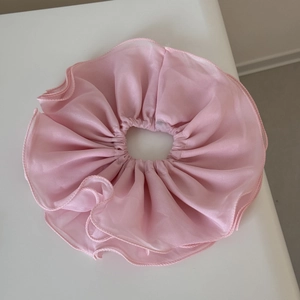 Gros plan d'un chouchou en mousseline rose double couche avec bords ondulés délicats