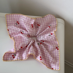 Vue détaillée du chouchou vichy rose avec motifs cerises et bordure au crochet jaune
