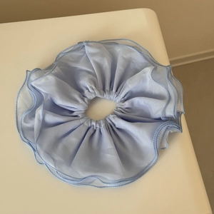 Détail de chouchou en mousseline bleu clair double couche avec bords ondulés fins