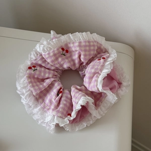 Vue détaillée du chouchou à carreaux roses avec broderie cerise et bordure dentelle