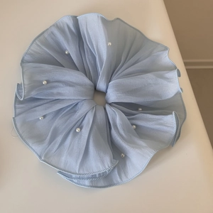 Detail view of light blue ruffled chiffon scrunchie with delicate white pearl embellishments