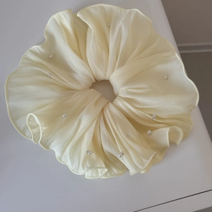 Close-up of cream pleated chiffon hair scrunchie with elegant white pearl trim detail