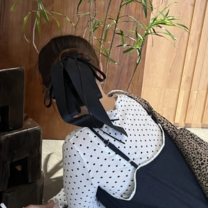 Détail de la pince à cheveux élégante avec nœud en satin noir et longs rubans en soie