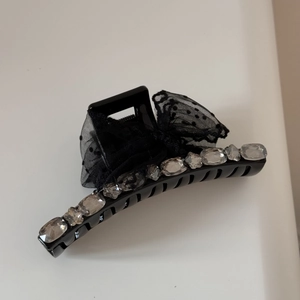 Detail of large black hair claw clip featuring rhinestones and polka dot tulle bow accent