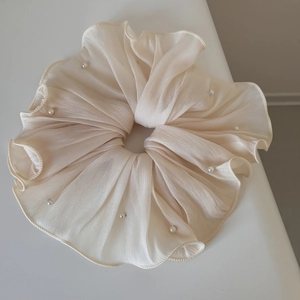 Close-up of pleated beige oversized hair scrunchie with delicate faux pearl accents