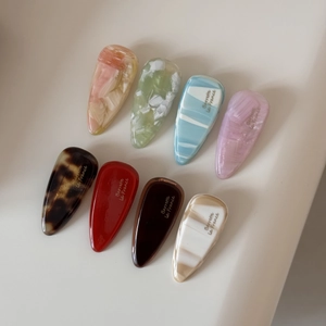 Huit barrettes en acétate coloré en forme de goutte avec motifs marbrés et texte français