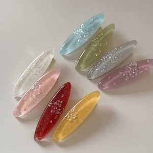 Flat lay of eight colorful oval resin hair clips with shell-like shimmer flakes for women