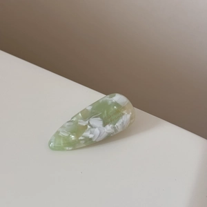 Détail d'une barrette goutte d'eau en acétate marbré vert à la surface polie