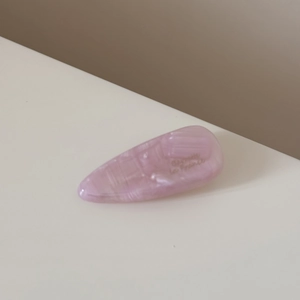 Détail macro d'une barrette à cheveux rose en acétate avec texture marbrée et gravure dorée