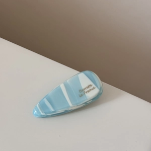 Détail d'une barrette goutte en acétate marbré bleu et blanc avec texte Barrette La France
