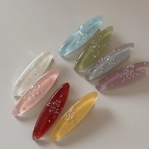 Detail view of oval resin hair clips with glitter sequins in various ocean colors
