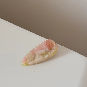 Détail de la pince à cheveux en acétate rose avec texture marbrée et forme de goutte