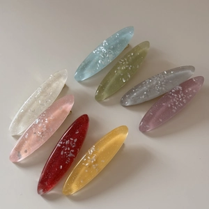 Detailed view of eight colorful oval resin hair clips with iridescent shell fragments