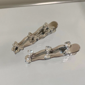 Close-up of silver bow hair clips with rhinestones and metallic wave design