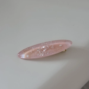 Detail of pink resin hair clip with embedded shell fragments and subtle glitter
