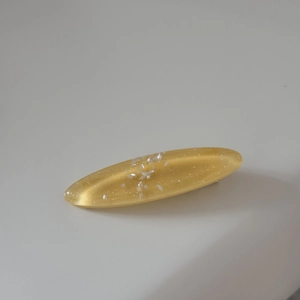 Detail of yellow resin hair clip featuring silver glitter and white shell fragments