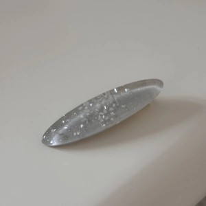 Detail of oval hair clip featuring grey translucent resin and silver glitter sparkles