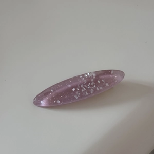 Macro detail of oval resin hair clip with glitter and shimmering seashell fragments