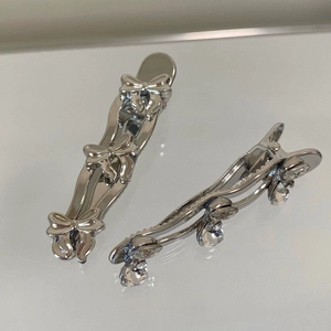 Detailed macro view of silver bow hair clips with crystal pendants and duckbill design