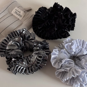 Detail view of metallic silver and black pleated scrunchies with shiny fabric texture
