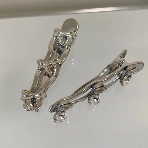 Close-up of silver bow hair clip and dangling rhinestone alligator clip set