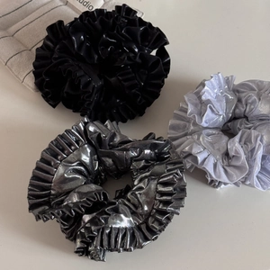 Close-up of metallic pleated scrunchies set in black, silver, and grey shades