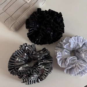 Close-up of metallic pleated oversized scrunchies in silver, grey and black colors