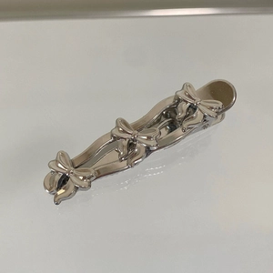 Detailed macro view of three silver metal bowknots on a polished wave hair clip