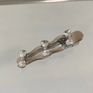 Detailed close-up of a silver bow hair clip with three sparkling rhinestone butterfly charms
