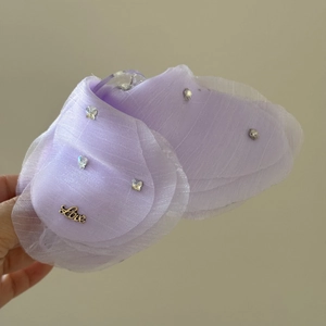 Dettaglio della molletta a farfalla in tulle viola con strass e scritta Love in metallo