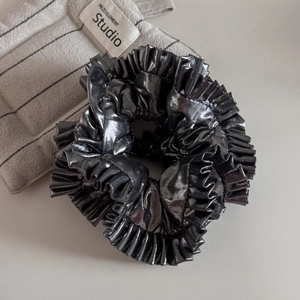 Detail of silver gray pleated hair scrunchie with metallic texture on fabric background