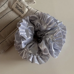 Macro shot of silver metallic oversized ruffled scrunchie with shiny pleated texture