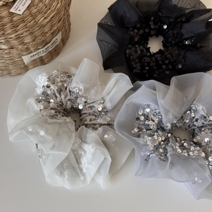 Vue détaillée de chouchous en organza noir et crème ornés de paillettes argentées brillantes