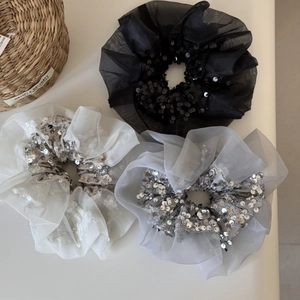 Gros plan de trois chouchous en organza scintillants en noir, blanc et gris argenté