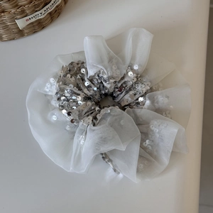 Détail d'un chouchou en organza blanc avec paillettes argentées et texture en maille