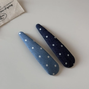 Gros plan sur des barrettes en denim bleu à pois avec une finition textile épurée