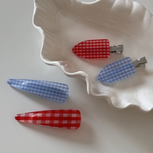 Detail showing red and blue plaid duckbill hair clips on a white seashell porcelain plate