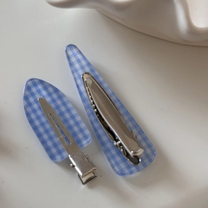 Macro detail of blue and white checkered hair clips with silver metal duckbill base