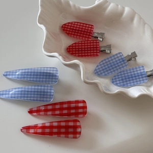 Vintage plaid hair clips in red and blue patterns on elegant ceramic plate