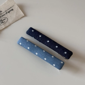 Vue détaillée de deux pinces à cheveux bleues à pois blancs avec texture en tissu