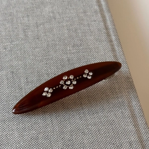 Detail of vintage tortoise acetate spring hair clip with sparkling rhinestone flower motifs