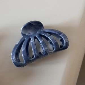Gros plan d'une pince à cheveux motif marbre bleu au design de pieuvre pour coiffure