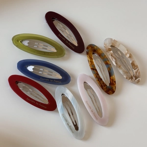 Flat lay of oval acetate hair clips in eight assorted colors and marbled patterns