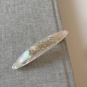 Macro shot of an iridescent acetate spring hair clip with flower-shaped rhinestones