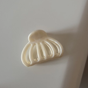 Détail de la pince à cheveux élégante blanc crème ajourée avec finition brillante