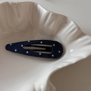 Gros plan d'une pince à cheveux bleue à pois blancs sur une assiette en céramique