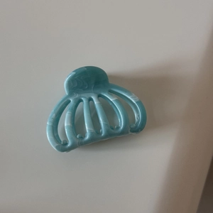 Détail de la pince à cheveux citrouille évidée avec texture marbre bleu et design à dents