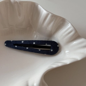 Gros plan d'une pince à cheveux à pois bleu marine sur une assiette décorative